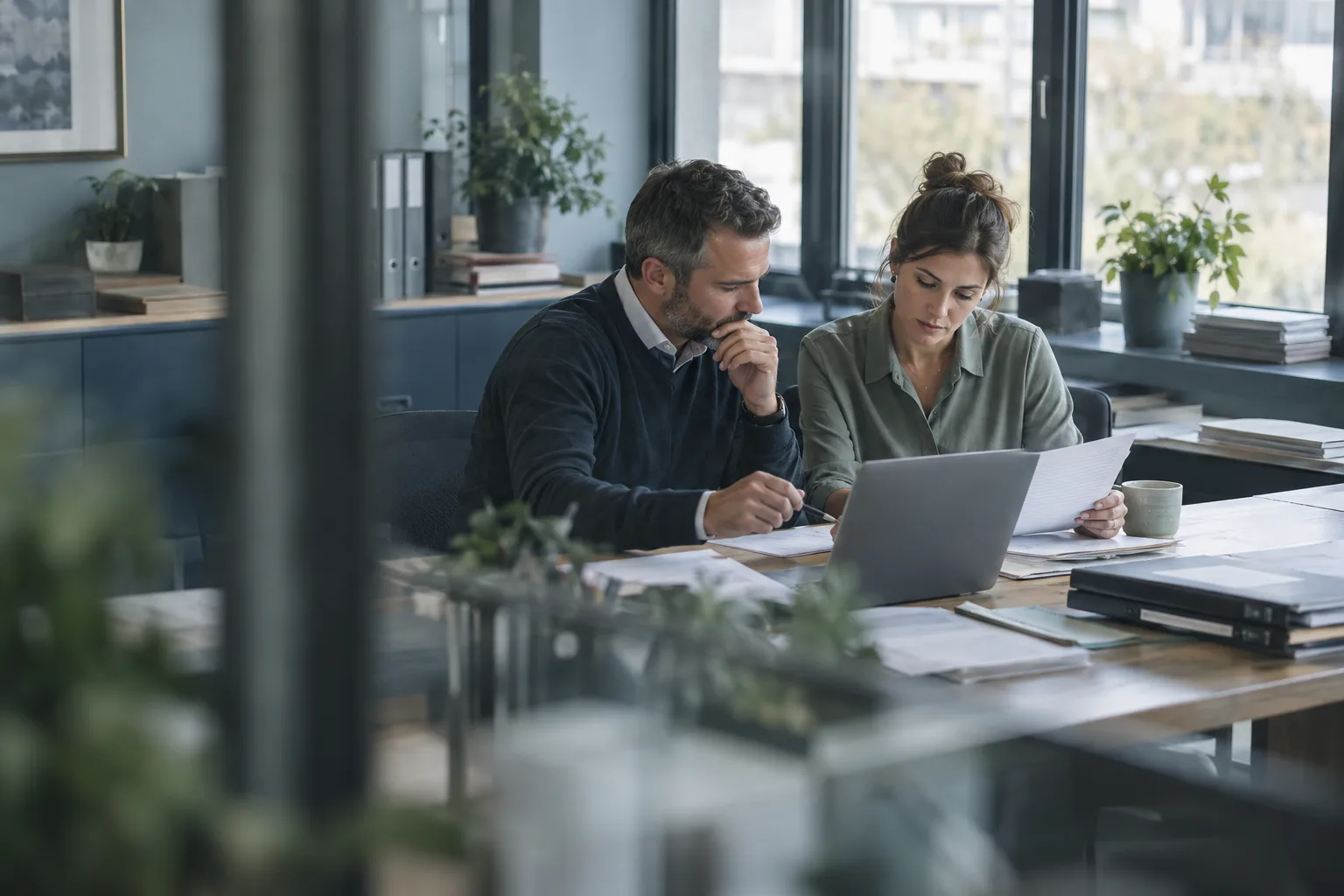 Two accountants reviewing client paperwork together at their desk.